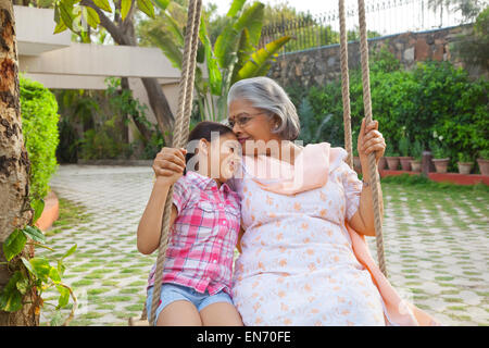 Grandmother and granddaughter sitting on a swing Stock Photo