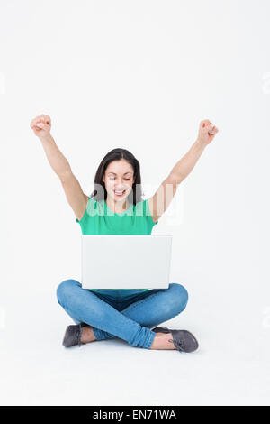 Happy brunette cheering in front of her laptop Stock Photo