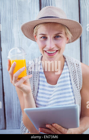 Pretty blonde woman using her tablet and holding orange juice Stock Photo