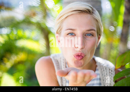 Pretty blonde woman smiling at the camera and blowing kiss Stock Photo