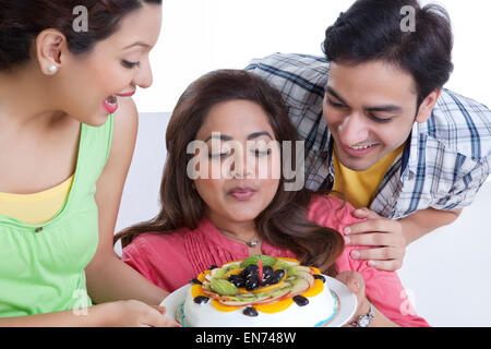 Woman blowing out candle on cake Stock Photo