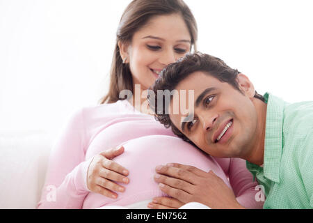 Man listening to pregnant wifes stomach Stock Photo