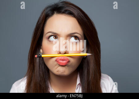 Female executive balancing pencil on lip Stock Photo