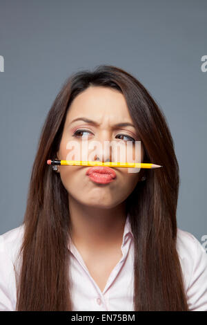 Female executive balancing pencil on lip Stock Photo
