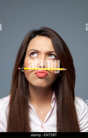 Female executive balancing pencil on lip Stock Photo