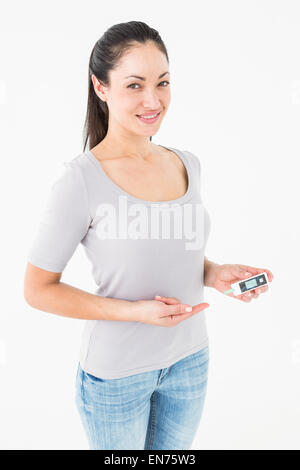 Diabetic brunette holding blood glucose monitor Stock Photo