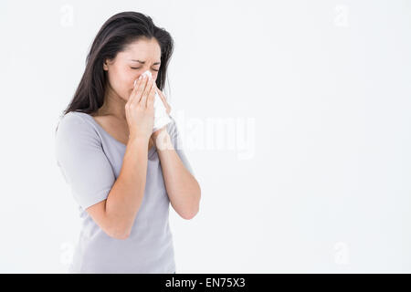 Sick brunette blowing her nose Stock Photo
