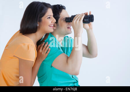 Young man and woman looking through binoculars Stock Photo