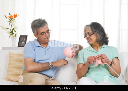 Husband helping while his wife is knitting Stock Photo