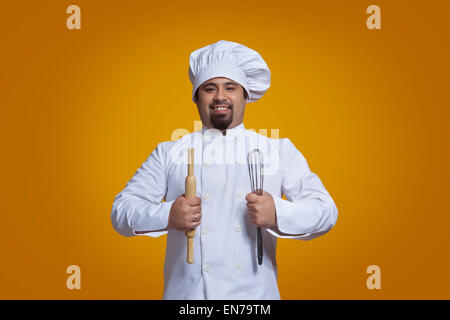 Portrait of chef holding wire whisk and rolling pin Stock Photo