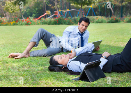 Businessman working in the park while businesswoman relaxes Stock Photo
