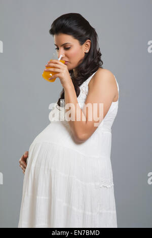 Young pregnant woman drinking juice in kitchen Stock Photo - Alamy