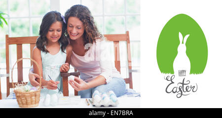 Composite image of happy mother and daughter painting easter eggs Stock Photo