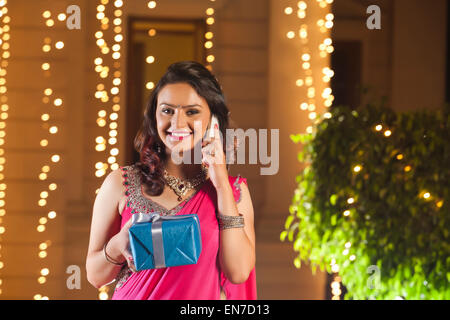 Portrait of woman with gift talking on mobile phone Stock Photo