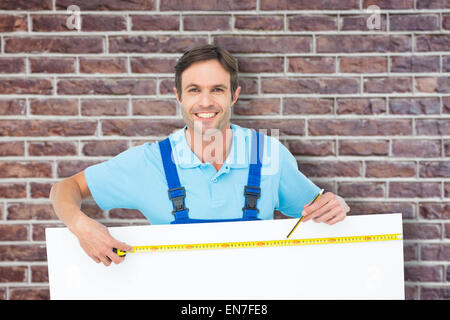 Composite image of happy carpenter measuring blank bill board Stock Photo