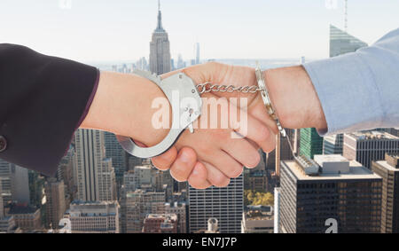 Composite image of business people in handcuffs shaking hands Stock Photo