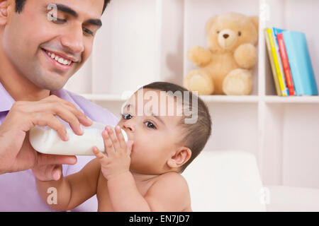 Man feeding baby with milk from bottle Stock Photo