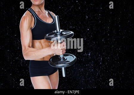 Composite image of female strong bodybuilder holding large black dumbbell Stock Photo