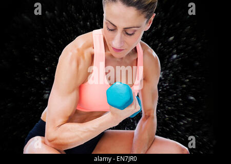 Composite image of strong woman doing bicep curl with blue dumbbell Stock Photo