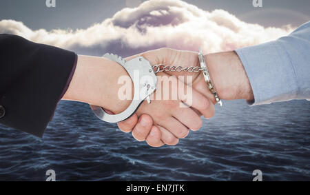 Composite image of business people in handcuffs shaking hands Stock Photo