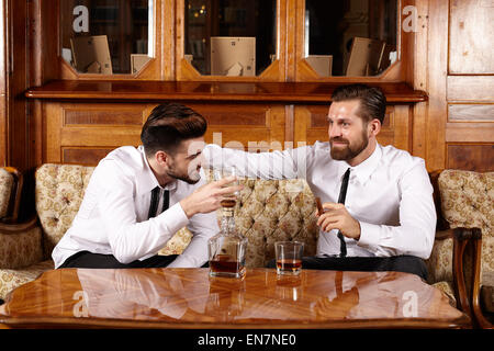 Two friends having a glass of whiskey and a nice conversation Stock Photo