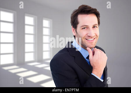 Composite image of businessman touching his chin while smiling at camera Stock Photo