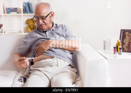 Old man giving himself insulin injection Stock Photo