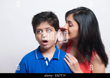 Sister whispering to her brother Stock Photo