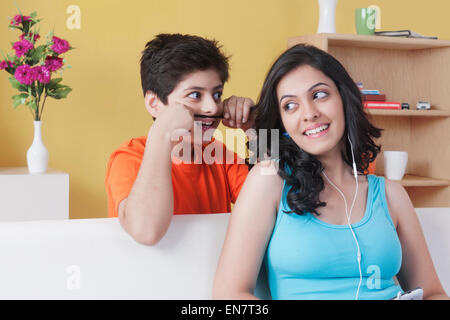 Boy standing behind his sister playing with her hair Stock Photo