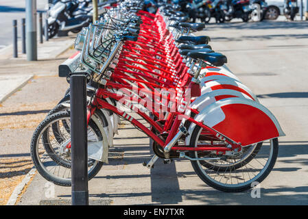 A row of rental bikes in their docking stands in downtown Barcelona, Catalonia, Spain Stock Photo