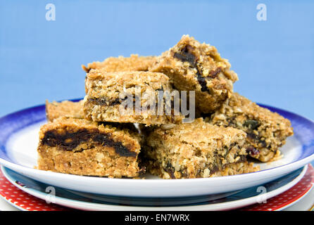 Home made date slices on pile of plates against a blue background Stock Photo