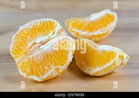 Half peeled orange on chopping board Stock Photo