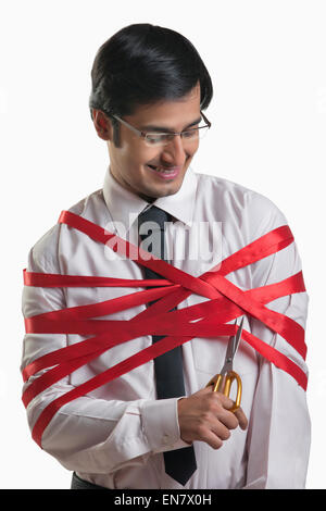 Businessman cutting his wrapped red ribbon Stock Photo