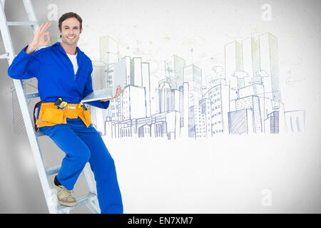 Composite image of confident repairman holding laptop while gesturing ok sign Stock Photo