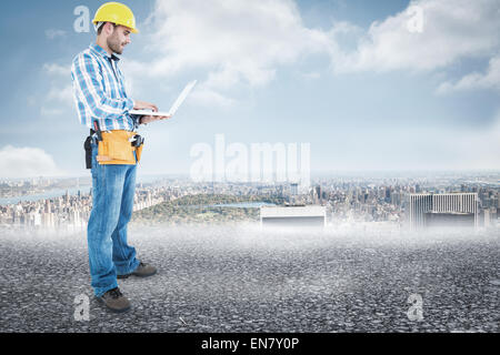 Composite image of full length of repairman using laptop Stock Photo