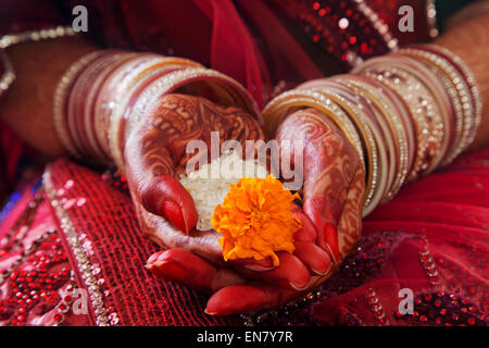 Close-up of a Brides hands performing marriage rituals with rice and marigold flower Stock Photo