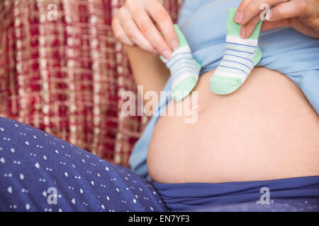 Pregnant woman holding baby shoes over bump Stock Photo