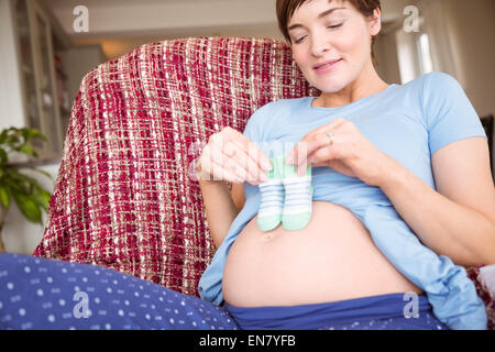 Pregnant woman holding baby shoes over bump Stock Photo