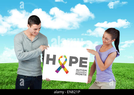 Composite image of young couple presenting banner together Stock Photo