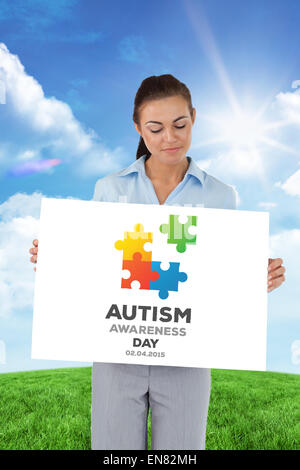 Composite image of businesswoman looking at the sign she is presenting Stock Photo