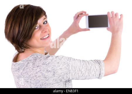 Pretty brunette looking at camera and taking a picture with her smartphone Stock Photo