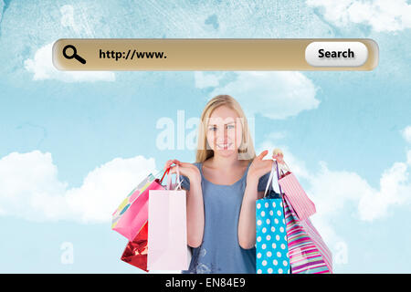 Composite image of pretty young blonde holding shopping bags Stock Photo