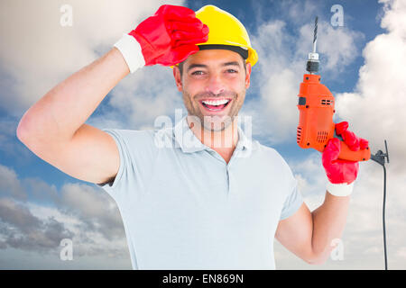 Composite image of smiling manual worker holding drill machine Stock Photo