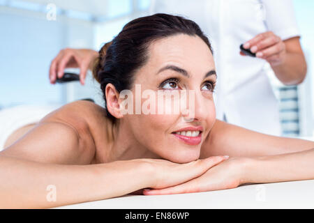 Smiling brunette getting hot stone massage Stock Photo - Alamy