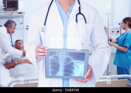 Composite image of doctor looking at xray on tablet Stock Photo