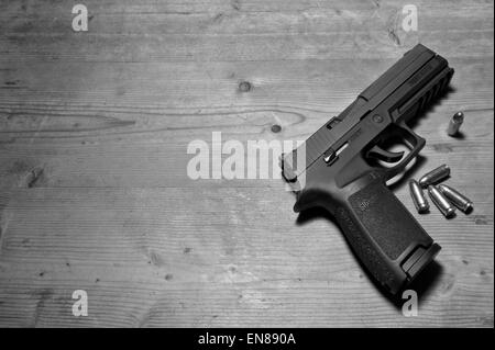 A Sig P250 semi-automatic gun with its 9mm.parabellum ammunition,suggesting murder,mystery,death,killing,pistol,shooting Stock Photo
