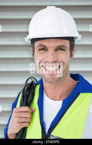 Composite image of happy electrician with wire against white background Stock Photo