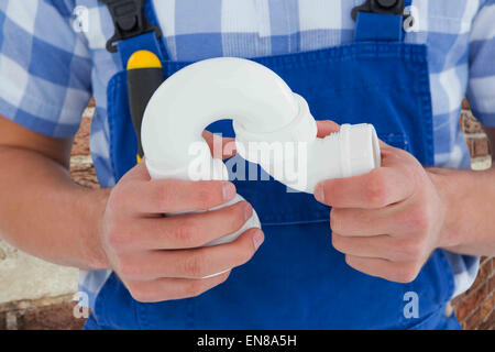 Composite image of plumber holding sink pipe on white background Stock Photo
