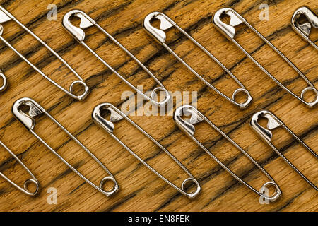 Pattern of safety pins or needles of metal. On old oak wood usable as background. Stock Photo