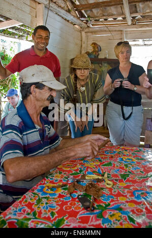 Vertical view of tourists watching a farmer roll cigars in Vinales. Stock Photo